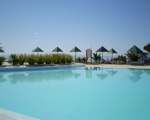 A large outdoor swimming pool with chaise lounge chairs and sunshades.