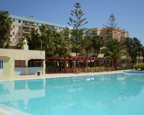 An outdoor swimming pool alongside resort units and trees.
