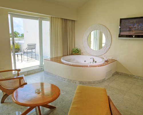 Interior view of a hot tub with chaise lounge chair and balcony with patio chairs.