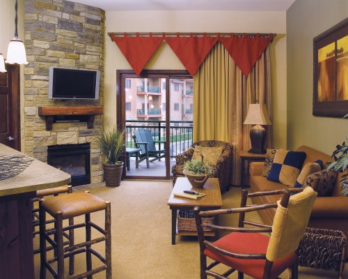 A WELL FURNISHED LIVING ROOM WITH A TELEVISION AND A BALCONY.