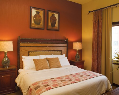 A WELL FURNISHED BEDROOM WITH A KING BED AND OUTSIDE VIEW.