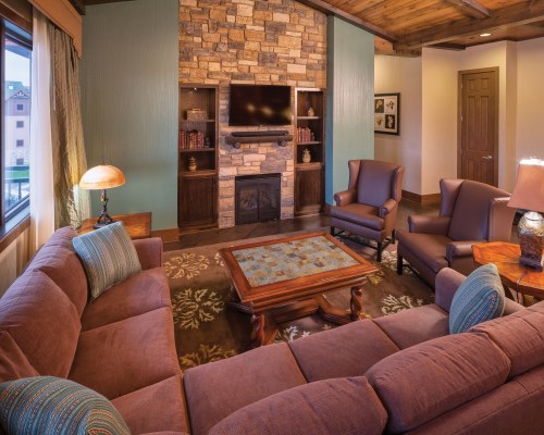A WELL FURNISHED LIVING ROOM WITH TELEVISION FIREPLACE AND OUTSIDE VIEW.