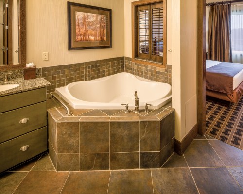 A BATHROOM WITH CLOSED SINK VANITY BATHTUB AND BEDROOM WITH A QUEEN BED.