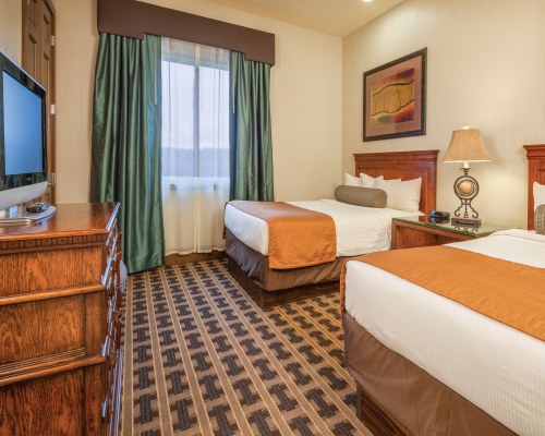A WELL FURNISHED BEDROOM WITH TWO QUEEN BEDS TELEVISION AND OUTSIDE VIEW.