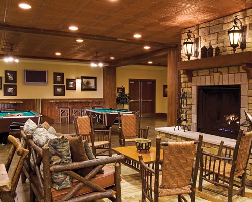 An indoor recreational room with a television fire in the fireplace and pool tables.