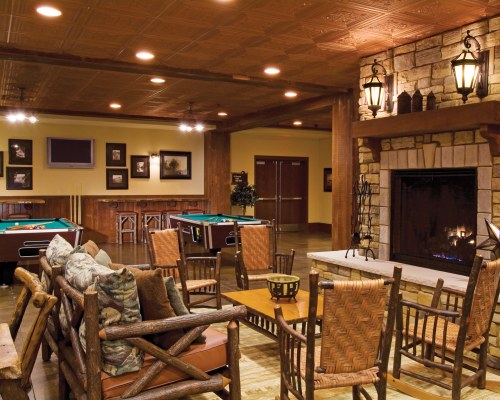 AN INDOOR RECREATIONAL ROOM WITH A TELEVISION FIRE IN THE FIREPLACE AND POOL TABLES.