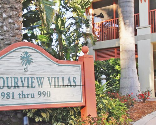 Signboard of the resort with shrubs and trees.