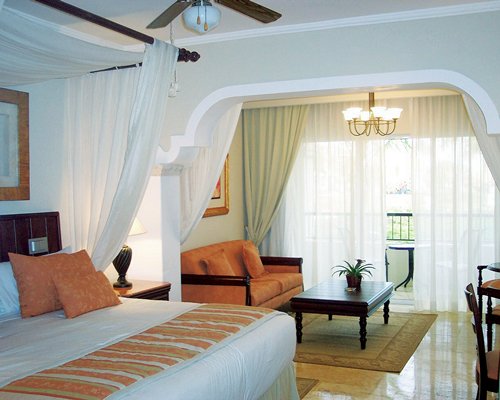 A well furnished bedroom with a king bed and balcony.