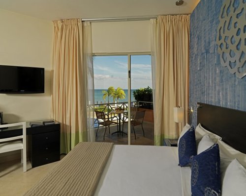 A well furnished bedroom with a television balcony and patio furniture.