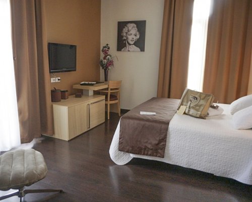 A well furnished bedroom with television and outside view.