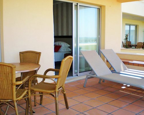 A balcony with chaise lounge chairs and patio furniture.