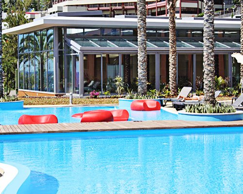 A large outdoor swimming pool with chaise lounge chairs and trees alongside resort units.