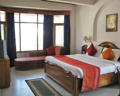 A well furnished bedroom with a television and an outside view.