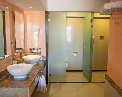 A bathroom with double sink vanity shower and separate toilet room.