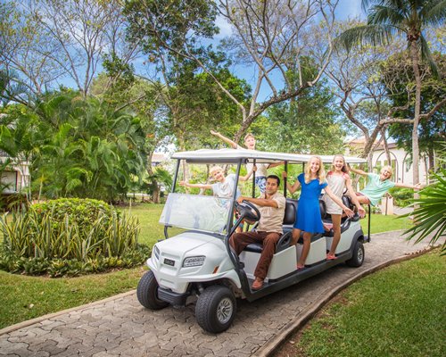 Children getting a ride on golf cart around landscaped gardens.