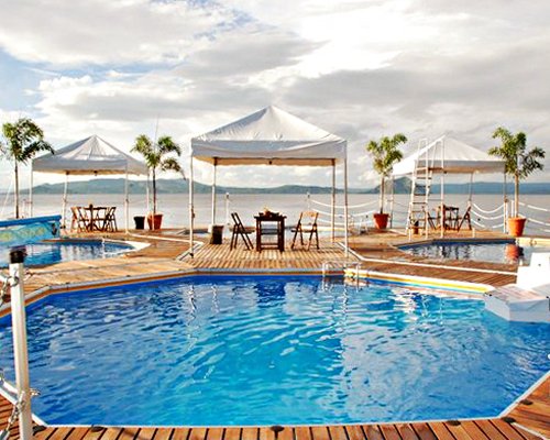 An outdoor swimming pool with patio furniture alongside the beach.