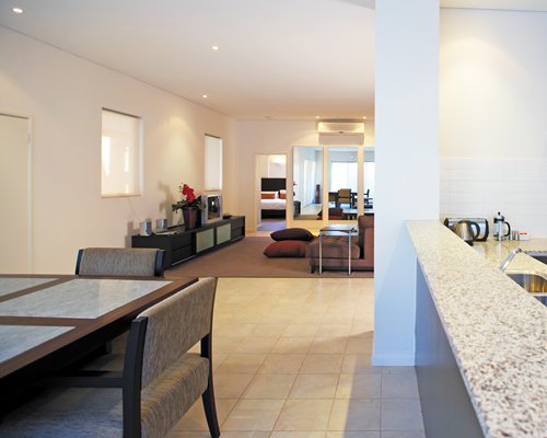 A well furnished living room with television open plan kitchen and dining area.