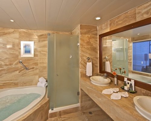 A bathroom with a bathtub shower and double sink vanity.