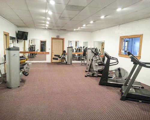 A well equipped indoor fitness center with television.