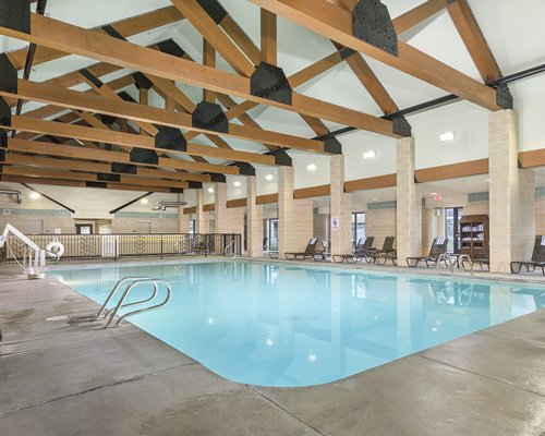 A large indoor swimming pool with chaise lounge chairs.