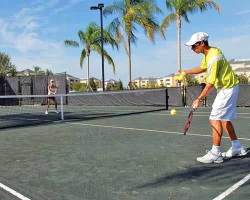 View of people playing tennis on an outdoor tennis court.