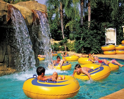 An outdoor swimming pool with water features and donut balloons.