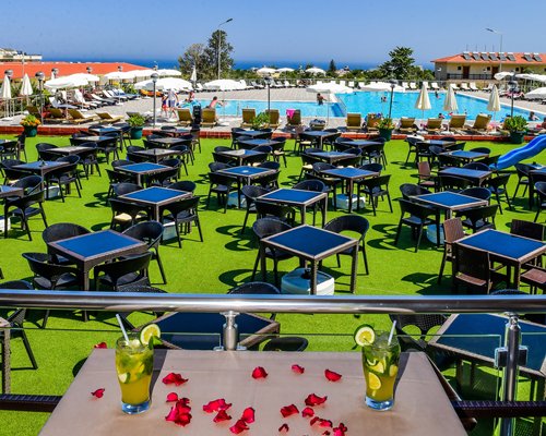 An outdoor swimming pool with chaise lounge chairs sunshades and trees alongside resort units.