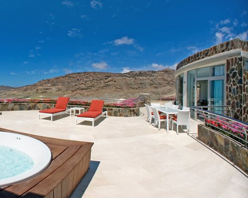 An outdoor hot tub with chaise lounge chairs alongside the resort unit.