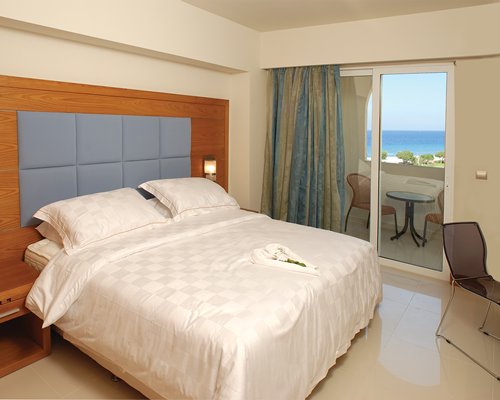 A well furnished bedroom with balcony patio furniture and sea view.