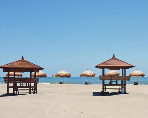 View of the beach with gazebos and thatched sunshades.
