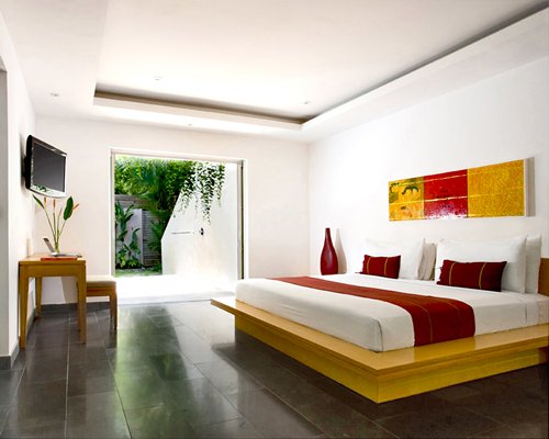 A well furnished bedroom with a king bed television and patio.