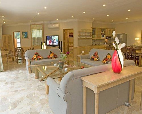 A well furnished living room with a television dining area and open plan kitchen.