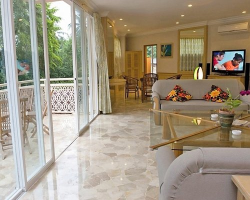 An open plan living room and dining area with a television and balcony.
