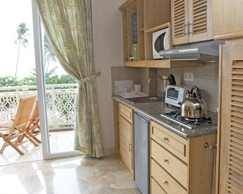 A well equipped kitchen with a microwave oven alongside a balcony.