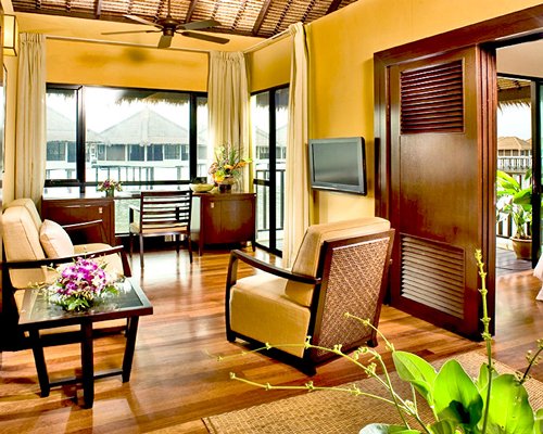 A well furnished living room with television and potted plants.