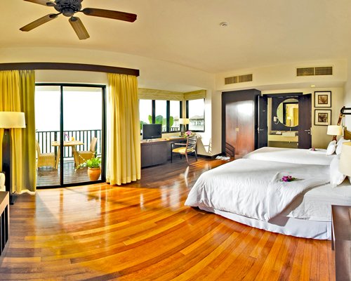 A well furnished bedroom with a television and balcony.
