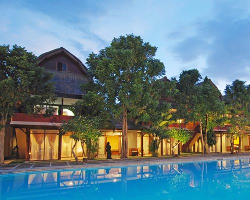 A large outdoor swimming pool with trees alongside resort units.