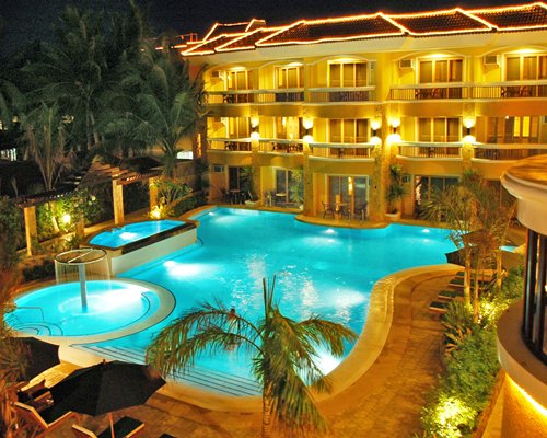 An outdoor swimming pool with a hot tub alongside resort units.