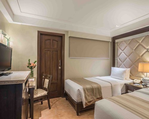 A well furnished bedroom with two single beds and a television.