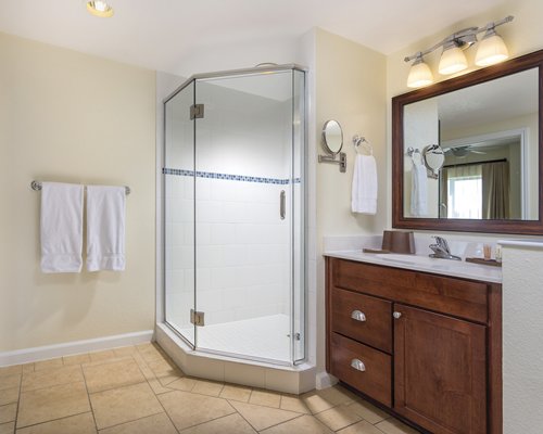 A bathroom with single sink vanity and a stand up shower.