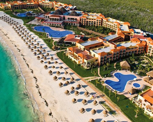 An aerial view of the resort with thatched sunshades on the shore of the sea.