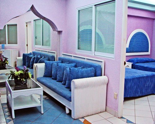 A well furnished living room alongside a bedroom with two beds.