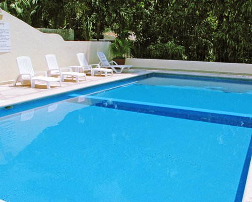 An outdoor swimming pool with chaise lounge chairs.