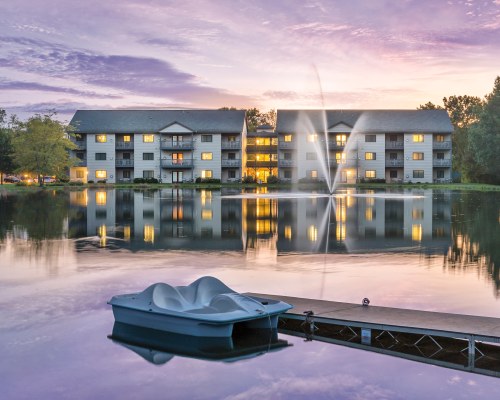EXTERIOR VIEW OF WYNDHAM TAMARACK ALONGSIDE THE LAKE WITH FOUNTAIN WOODEN PIER AND A PADDLE BOAT.