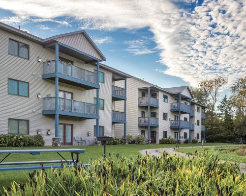 SCENIC EXTERIOR VIEW OF MULTI STORY RESORT UNITS WITH PATIO FURNITURE.