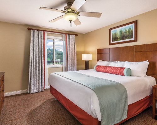 A WELL FURNISHED BEDROOM WITH A QUEEN BED AND OUTSIDE VIEW.