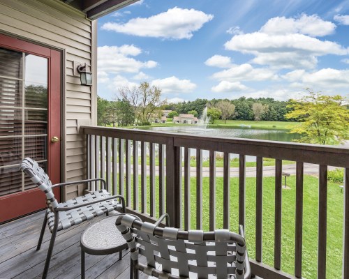 VIEW OF THE LAKE AND LANDSCAPED PATHWAY FROM THE BALCONY WITH PATIO FURNITURE.