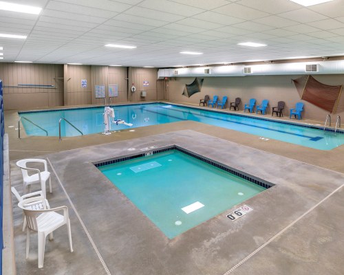 INDOOR SWIMMING POOL AND HOT TUB WITH PATIO CHAIRS.