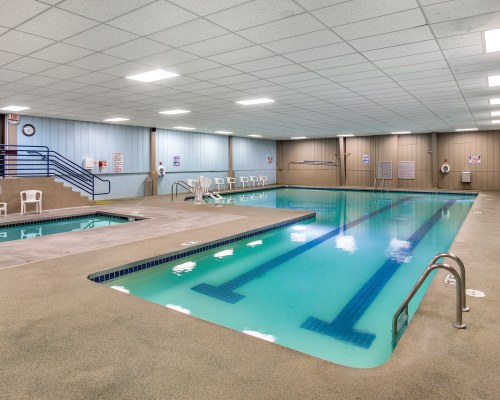 INDOOR SWIMMING POOL AND HOT TUB WITH PATIO CHAIRS.