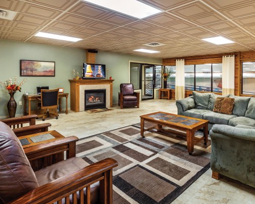 A WELL FURNISHED LARGE LIVING ROOM WITH A TELEVISION PULL OUT SOFAS AND A FIRE AT THE FIREPLACE.